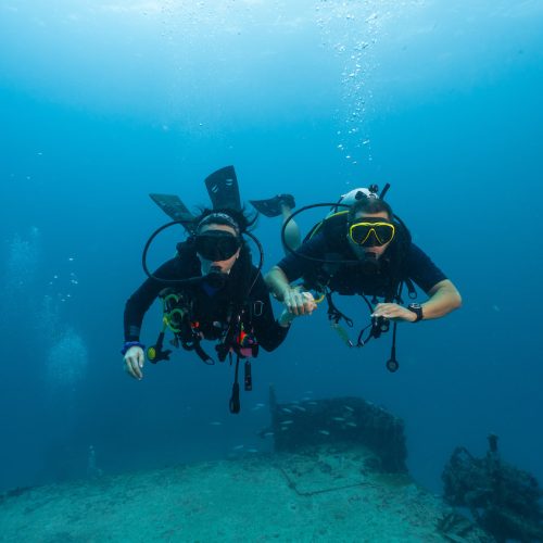 couple of divers posing in front of a sunken ship, technical diving