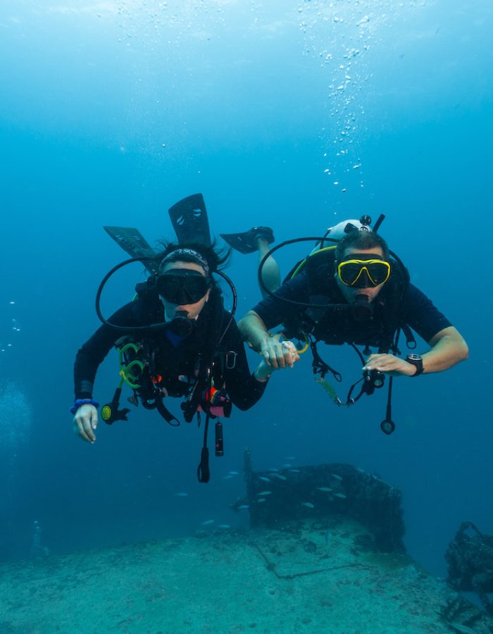couple of divers posing in front of a sunken ship, technical diving